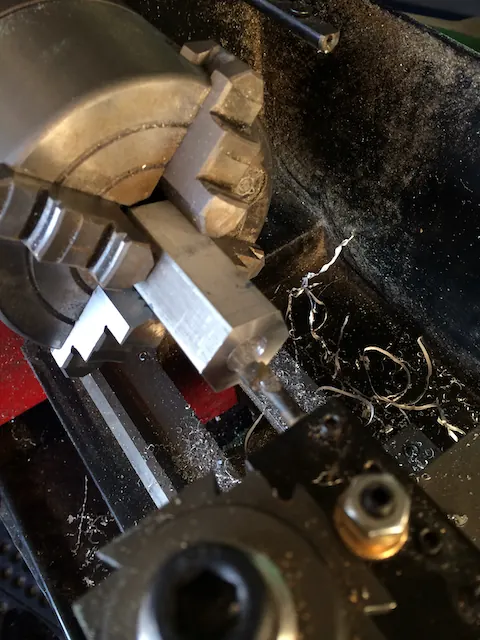 A part clamped in a lathe chuck, aluminum swarf around it