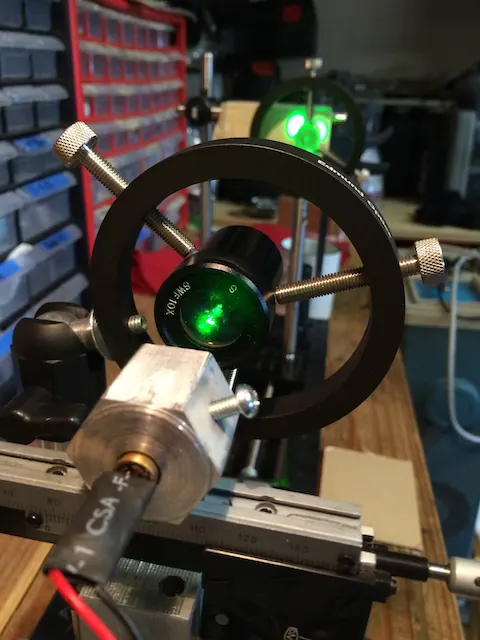 A green laser through an optic mount on a wooden bench