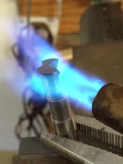 A torch flame heating a machined part