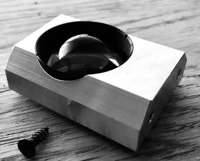 Black and white photo of a machined aluminum block holding a lens