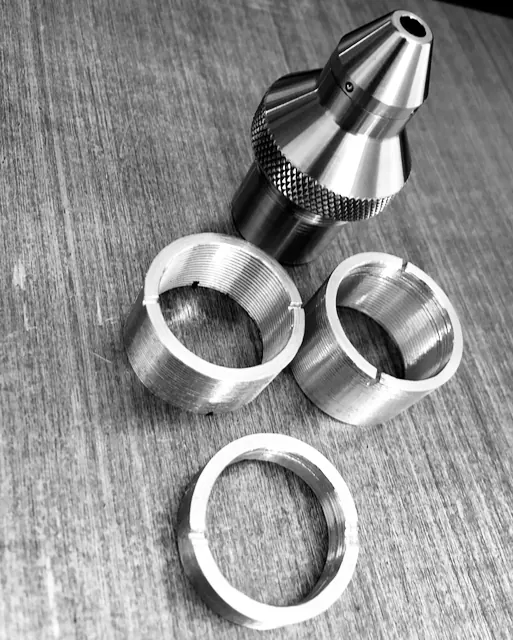 Black and white photo of machined lens tube parts and rings
