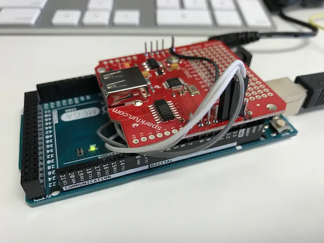 An Arduino board with a red prototyping shield