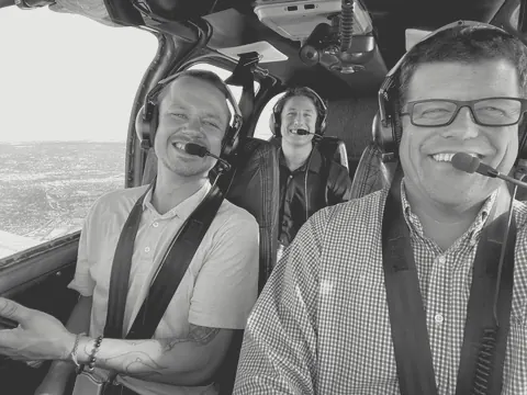 Three ARC team members smiling in the cockpit of a small plane