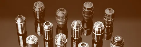 A row of microscope objectives standing on a dark surface